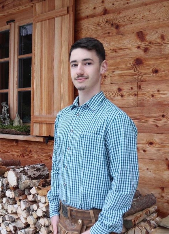 Mann in Tracht vor einer Hütte